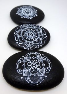 three black rocks with white designs on them