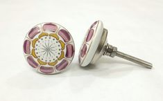 a pair of pink and yellow flowered ceramic knobs on a white table top