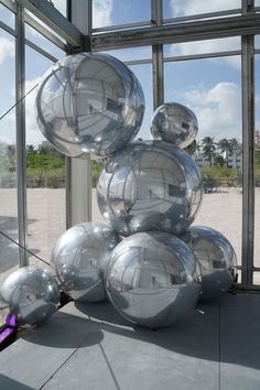 a bunch of shiny balls sitting on top of a cement floor next to a window