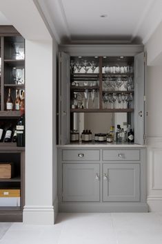 an open cabinet in the middle of a room with wine glasses on it and other bottles