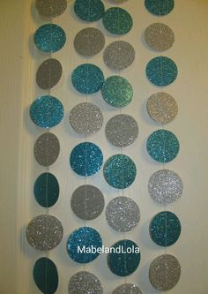 a number of circles hanging from a wall with glitter on the bottom and one circle in the middle