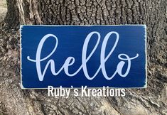 a wooden sign that says hello on it next to a tree with the words rubby's creations