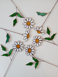 a group of white and yellow flowers sitting on top of each other next to green leaves