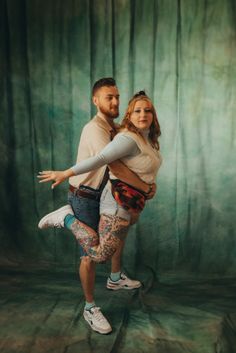 a man and woman are dancing together in front of a green backdrop with leaves on it