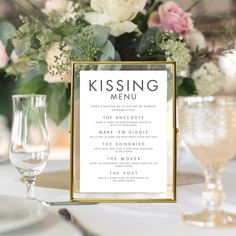 a table setting with menus and wine glasses on the table, along with flowers in vases