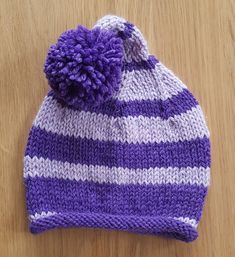 a purple and white knitted hat with a pom - pom