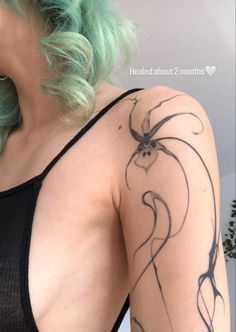 a woman with green hair has a spider tattoo on her left arm and shoulder, while wearing a black tank top