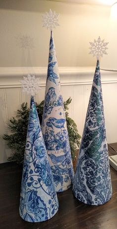 three blue and white christmas trees sitting on top of a wooden table