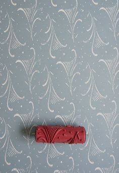 a red object sitting on top of a blue wallpaper covered in white swirls