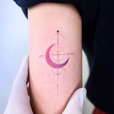 a person with a tattoo on their arm holding up a pink and purple half - moon