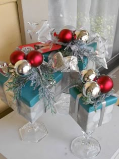 two wine glasses filled with christmas decorations on top of a table next to a window