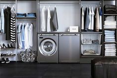 a washer and dryer in a room with clothes hanging on the shelves,