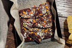 chocolate barkle with nuts and other toppings on a wooden table next to chips