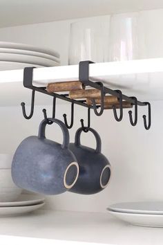 pots and pans are hanging from hooks on the kitchen shelf above the stovetop