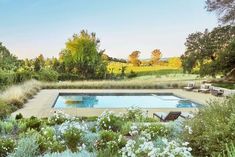 an outdoor swimming pool surrounded by flowers and trees