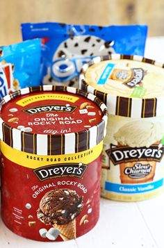 three ice creams are sitting next to each other on a white table with snacks