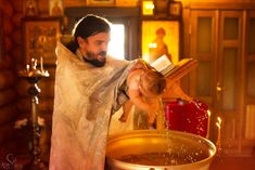 a man in a robe pouring water into a large metal bowl on top of a table