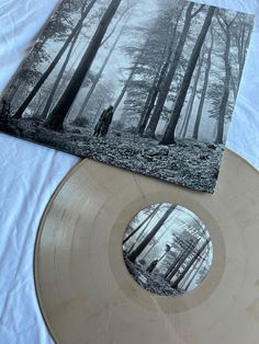 an image of a person standing in the woods on a white shirt next to a vinyl record