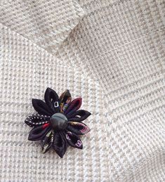 A black lapel flower pin boutonniere made in the Japanese tsumami kanzashi style, for men and women! This attention-grabbing pin is a unique fashion accessory no one else can own. I used 10 different mostly black silk fabrics for the flower, affixed a teardrop obsidian coin bead into Black Lapel Pin Brooch For Gift, Black Brooch Lapel Pin As Gift, Black Lapel Pin Brooch As Gift, Black Formal Brooch Lapel Pin, Elegant Black Lapel Pin For Formal Occasions, Black Formal Lapel Brooch, Black Brooches With Handmade Flowers For Gift, Black Handmade Flowers Brooches For Wedding, Handmade Flower Black Brooches For Gifts