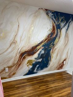 a large painting on the wall in a room with wood flooring and walls painted white, gold and blue