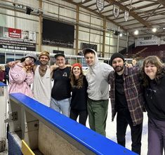 a group of people standing next to each other in front of a conveyor belt