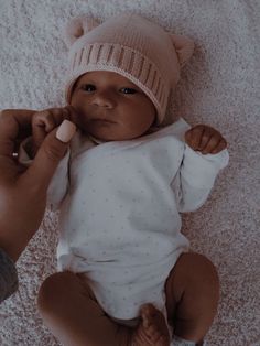 a baby is laying on the floor and being held by someone's hand with a toothbrush in its mouth