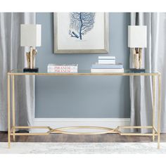 a console table with books and lamps on it in front of a blue painted wall