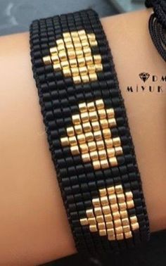 a close up of a person's arm wearing a bracelet with gold squares on it