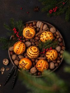 some oranges and nuts in a bowl with pine cones on the table next to them