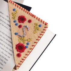 a piece of felt with flowers on it next to an open book that has the letter j on it