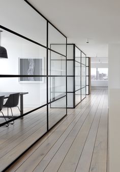 an empty room with wooden floors and glass partitions on the wall to divide it from the rest of the room