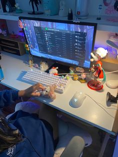 a person sitting at a desk with a keyboard and mouse in front of a computer monitor