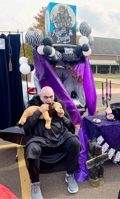 a man sitting on the back of a truck holding a stuffed animal in his lap