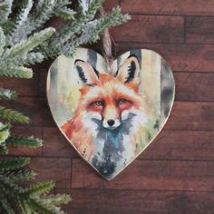 a wooden heart with a painting of a fox on it hanging from a pine tree