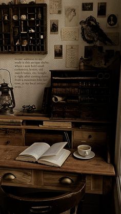 an open book on top of a wooden desk next to a cup and saucer