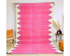 a large pink and white rug with fringes on the floor next to a chair