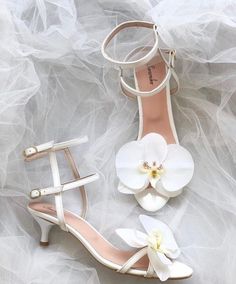 two pairs of white shoes with flowers on the heel and one pair of high heels