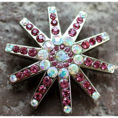 a red and white brooch sitting on top of a stone floor next to a rock