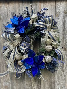 a wreath with blue and silver decorations hanging on a wooden fence