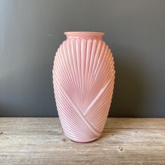 a pink vase sitting on top of a wooden table