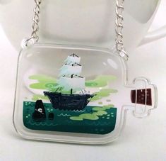 a glass keychain with a boat in the water on it's side