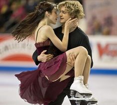 a man and woman skating on ice with their arms around each other's shoulders