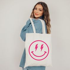 "Oh yesss, this awesome preppy aesthetic tote bag with Smiley Face with lightning eyes print is definitely a real eye-catcher! Just fun to use as a school bag or reusable bag. It will hold all of your preppy stuff. Just perfect! Yes we know, this bag is a real everyday musthave and very fashionable. Love yourself and buy one for you and your best friend or anyone else that loves happy and smiley emojis! * Good to know: Kindly note that the bag has no extra pockets or zipper closure * Material: Sustainable 100% cotton canvas * Color tote: Natural or black * Size: The tote measures 15.0\"- 38.0 cm in width and 16.5\"- 42.0 cm in heigth to be carried on your shoulder or hand, its capacity is 10L. Kindly note that slight differences in size are possible * Note: The design on each bag is hand-p Trendy Canvas Bag With Graphic Print For Everyday Use, Trendy Graphic Print Canvas Bag For Everyday Use, Trendy School Bags With Graphic Print, Trendy Graphic Print Shoulder Bag For Everyday, Trendy Graphic Print Canvas Tote Bag, Trendy White Shoulder Bag With Graphic Print, White Trendy Canvas Bag With Graphic Print, Trendy Everyday Bags With Graphic Print, Trendy White Canvas Bag With Graphic Print