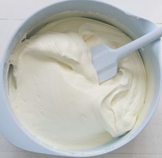 a blue bowl filled with white frosting on top of a table