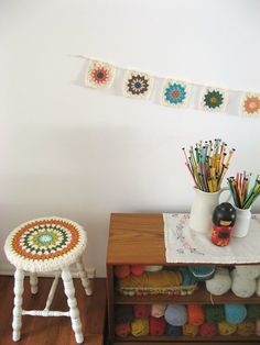 there are crocheted doily hanging on the wall next to two stools