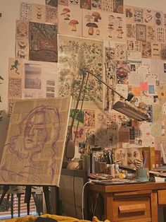 a messy room with lots of papers and pictures on the wall, including a lamp