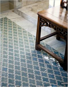 a wooden table sitting on top of a tiled floor next to a bath room door