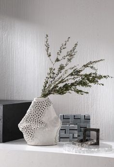 a white vase sitting on top of a table next to a black and white object