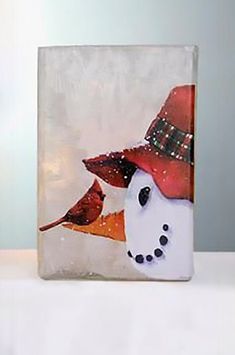 a glass block with a snowman wearing a red hat and a bird on it