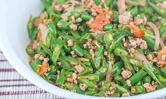 a white bowl filled with green beans and meat